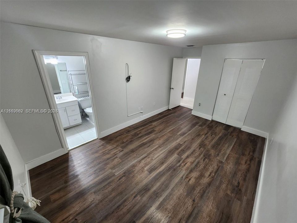 Wood-finish flooring, white paneled interior doors, and a ceiling-mounted flush-mount light fixture