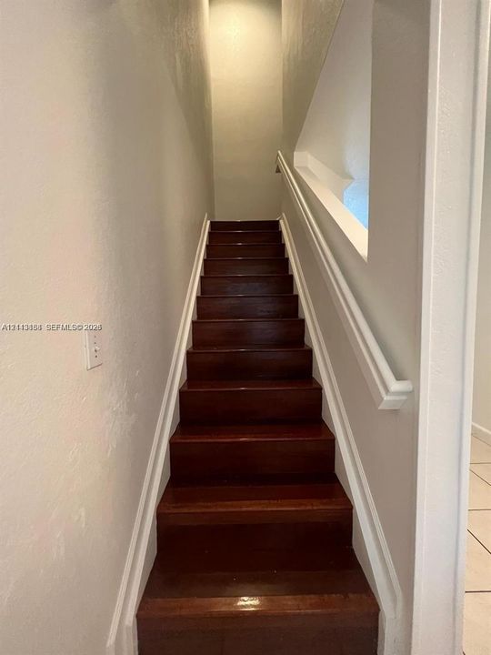 Staircase featuring wood-finish treads and a white painted handrail