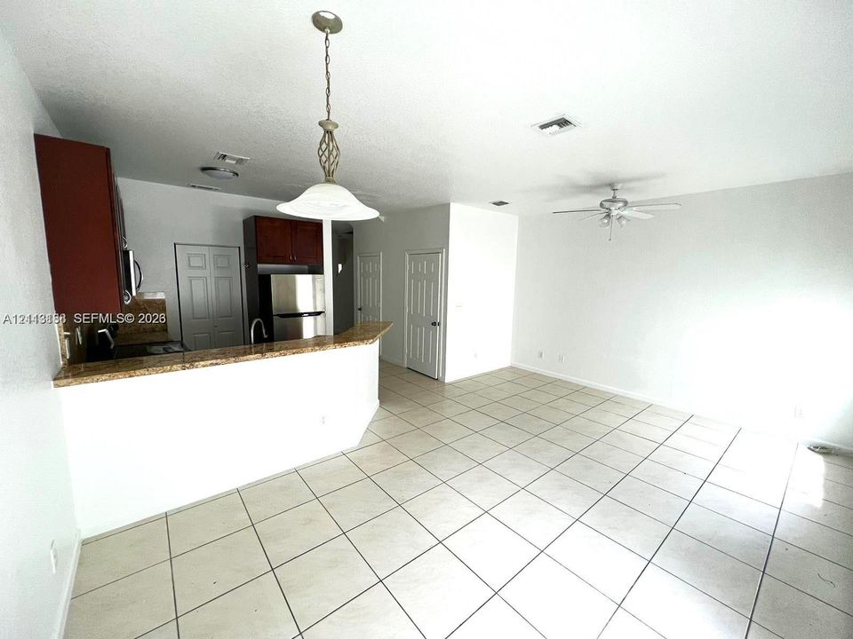Kitchen featuring stone-finish countertops, dark wood-tone cabinetry, stainless steel appliances, ceramic tile flooring, and a pendant light fixture