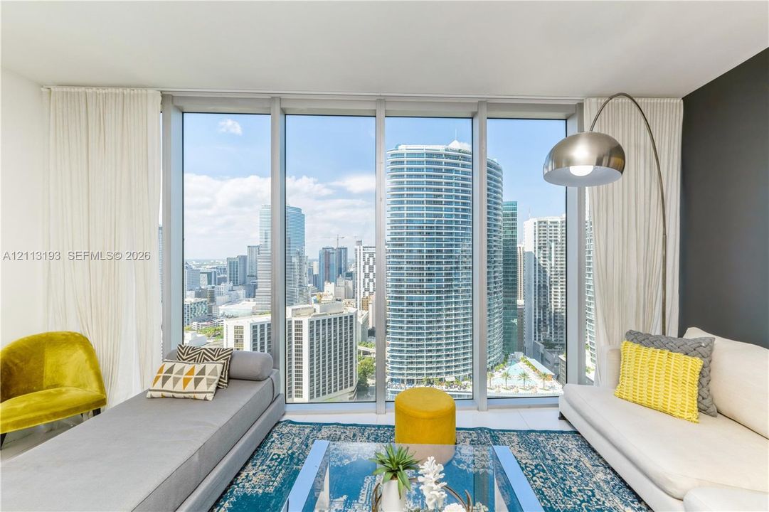 Floor-to-ceiling windows featuring expansive urban panoramas, sleek white tile flooring, and a neutral wall color palette
