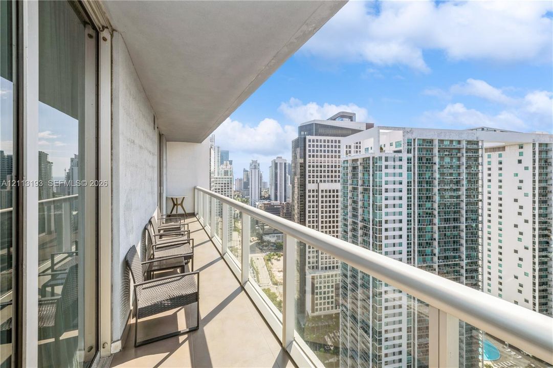 Private covered balcony featuring a glass and metal railing system with panoramic urban skyscraper scenery