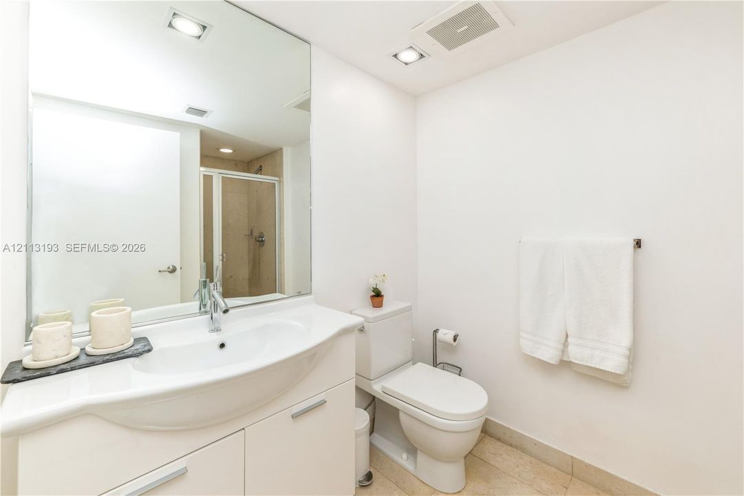 Bathroom featuring a white vanity with an integrated basin, a polished chrome faucet, a full-wall mirror, recessed lighting, and tile flooring
