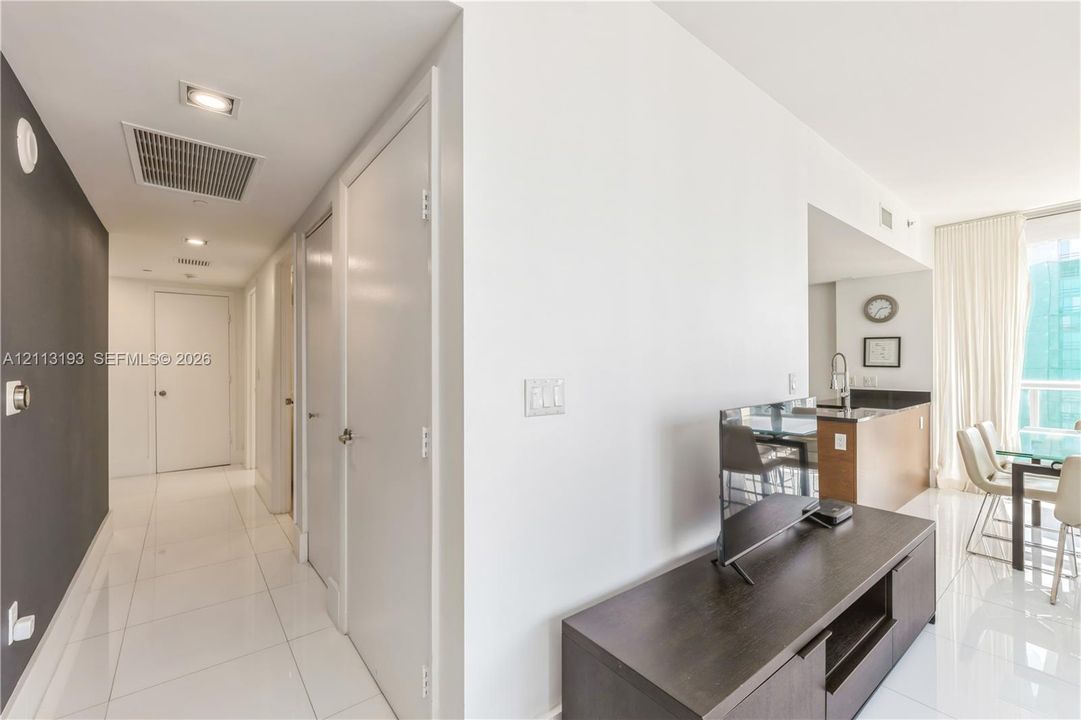 Interior hallway featuring polished tile flooring, recessed ceiling lighting, and contrasting dark-toned accent wall