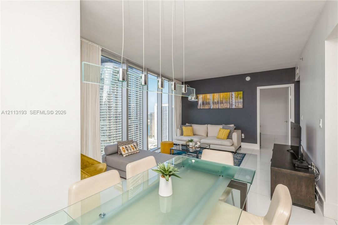 Floor-to-ceiling windows, polished tile flooring, contemporary multi-pendant lighting fixture, and a bold accent wall