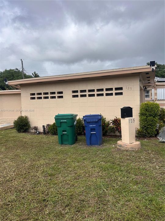 Concrete block exterior featuring decorative horizontal vents and a ground-mounted pedestal mailbox