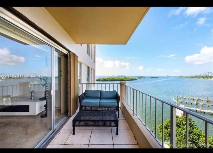 Covered private balcony with tiled flooring and metal railing overlooking the water