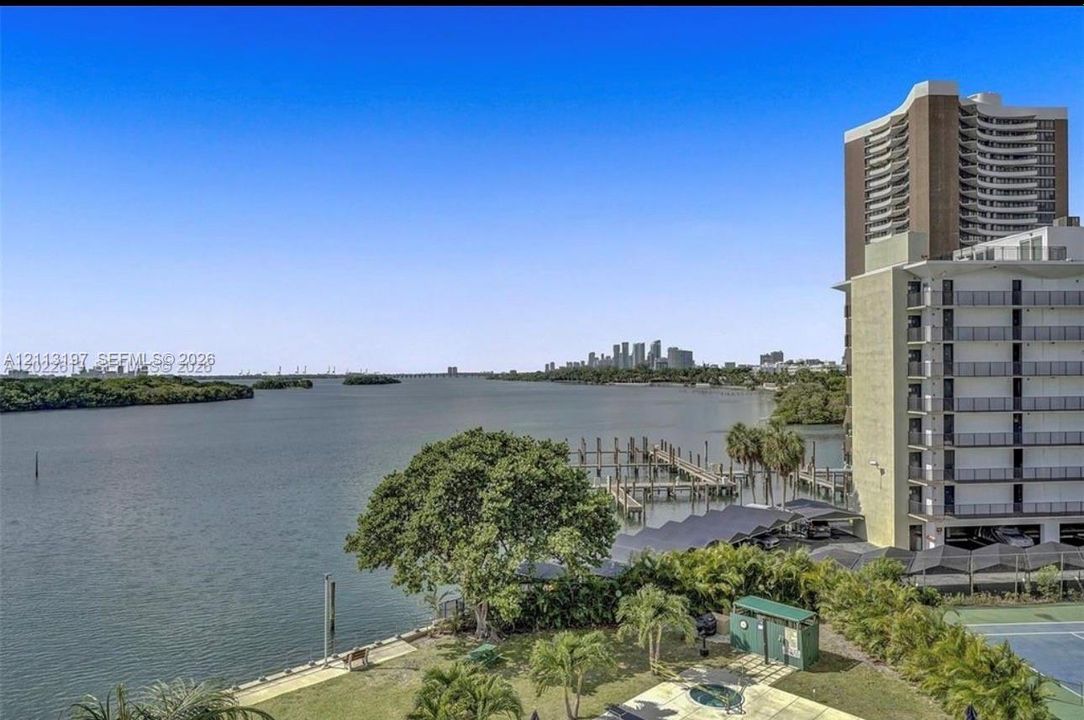 Waterfront property featuring a private boat dock, tennis court, and mature landscaping