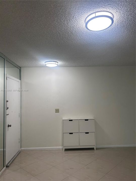 Interior space featuring neutral wall tones, large-format tile flooring, dual round flush-mount ceiling fixtures, and mirrored wall panelling