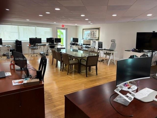 Expansive workspace featuring wood-finish flooring, recessed lighting, and a suspended drop ceiling