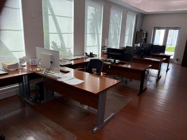 Spacious interior featuring wood-finish flooring, tray ceiling, multiple floor-to-ceiling windows, and double-door exterior access