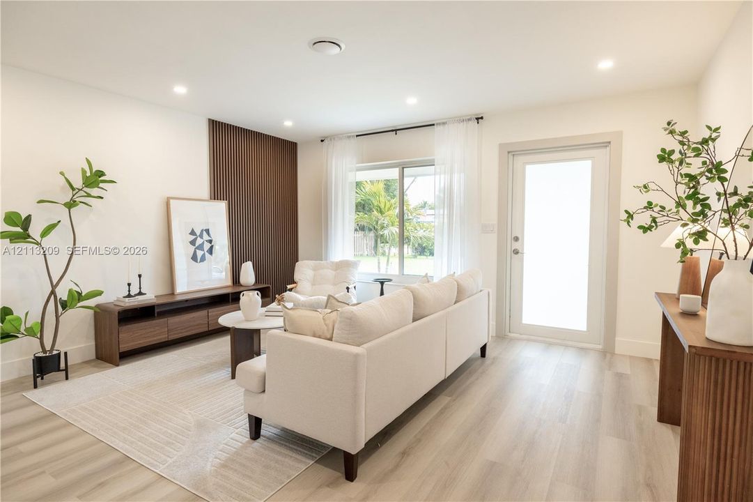 Living space featuring wood-finish flooring, vertical slat accent wall, recessed lighting, and a frosted glass-panel exterior door