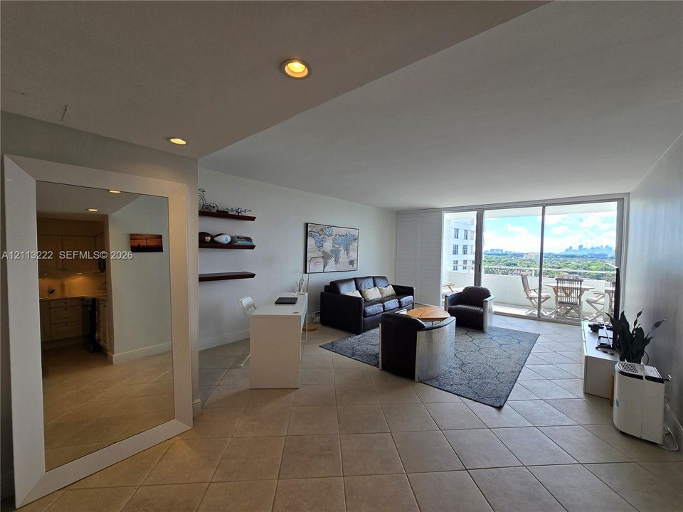Open-concept living space featuring diagonal tile flooring, recessed lighting, built-in shelving, and large floor-to-ceiling sliding glass doors leading to a balcony