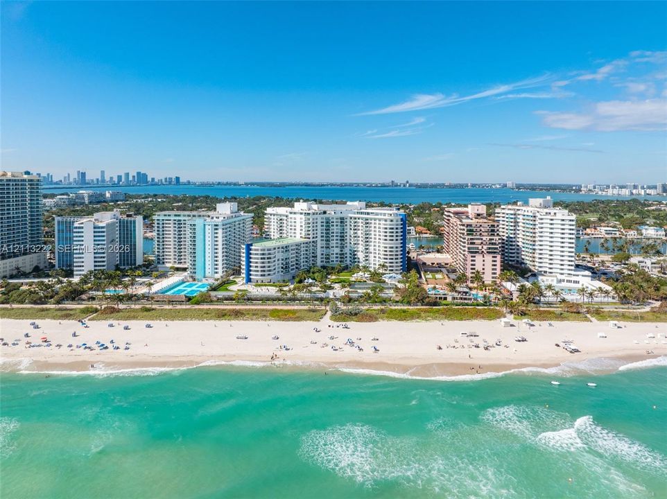 Aerial perspective of beachfront high-rise properties featuring direct access to sandy shorelines, coastal water exposure, and multi-story architectural structures