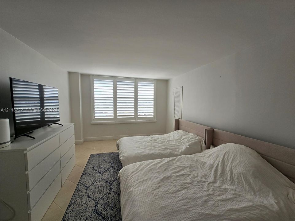 Room featuring neutral-toned tile flooring and white interior shutters