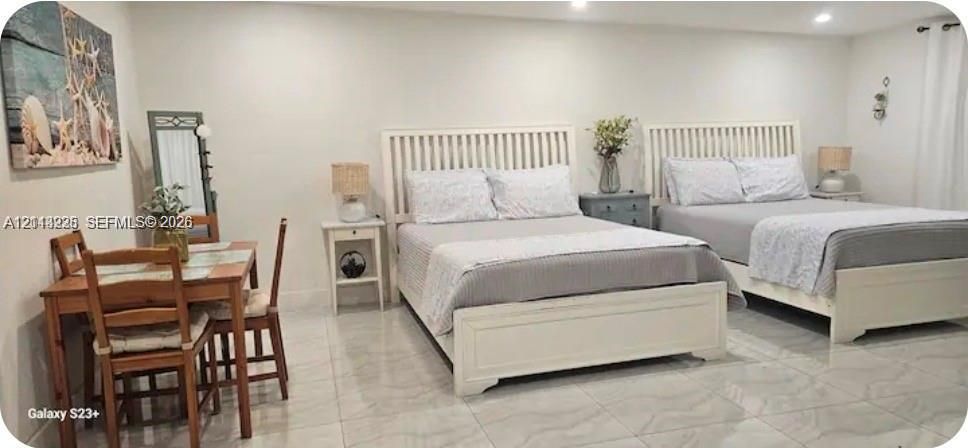 Neutral-toned interior space featuring light-colored polished tile flooring and recessed ceiling lighting