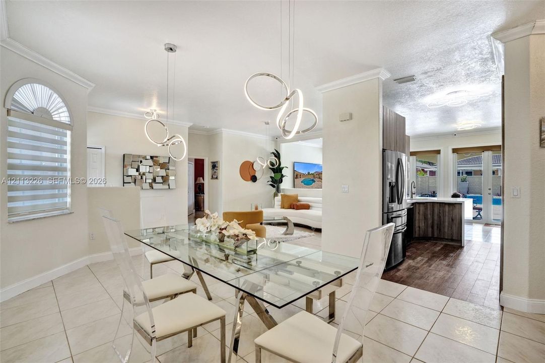 Interior space featuring ceramic tile flooring, modern circular LED pendant lighting, arched window with decorative detailing, and wood-finish cabinetry