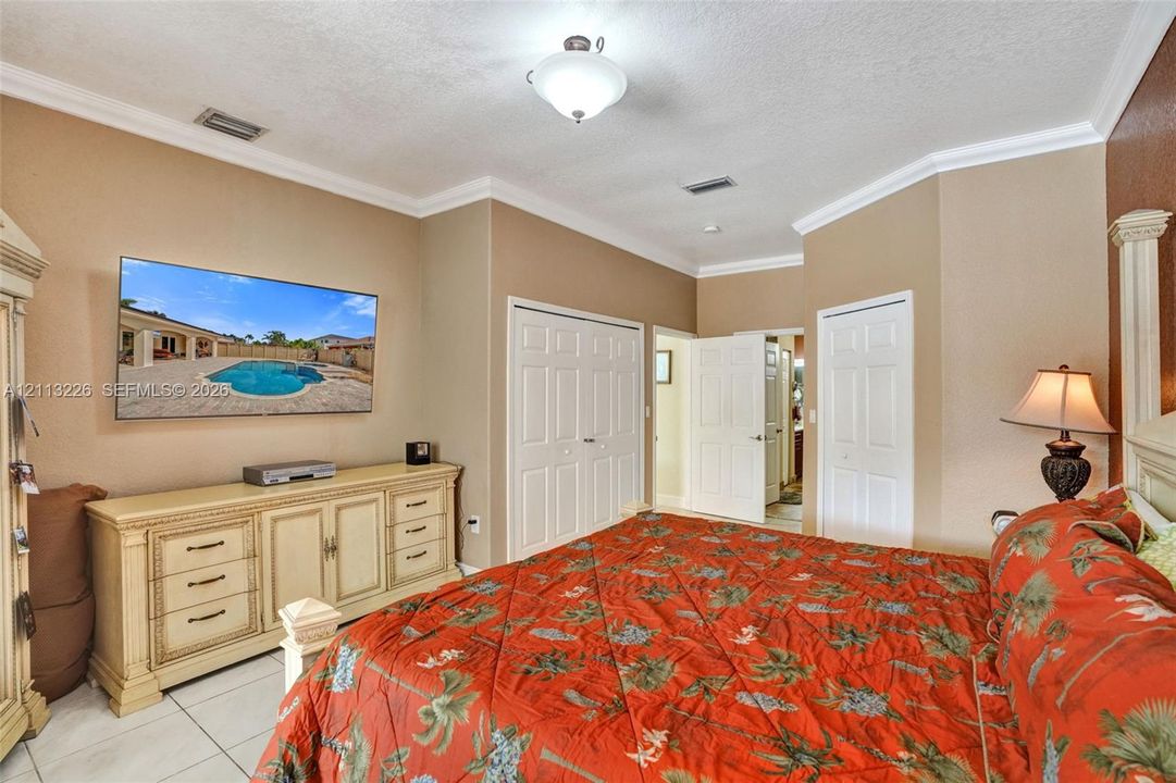 Room featuring crown molding, neutral wall finishes, tile flooring, and dual-panel closet doors