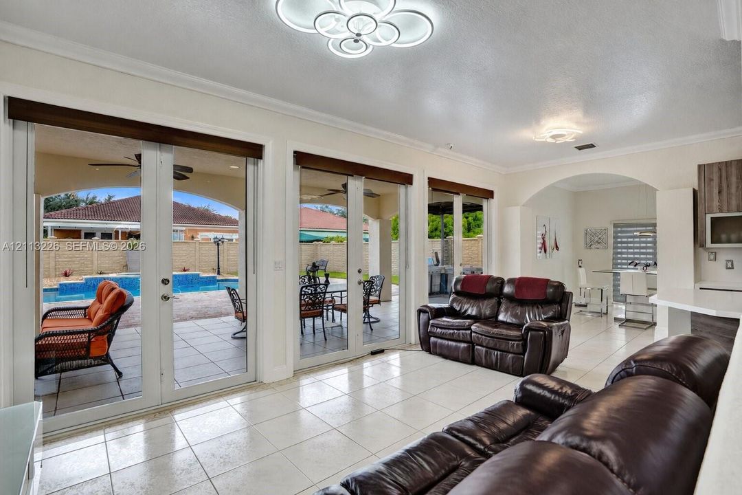 Main living area featuring tile flooring, multi-panel glass French doors, architectural archway, and geometric LED ceiling lighting