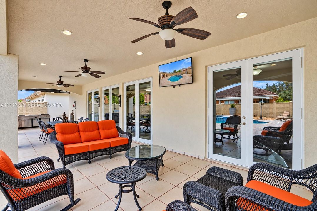 Covered patio featuring ceramic tile flooring, recessed lighting, ceiling fans, and dual sets of French doors