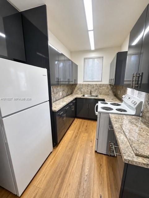 Kitchen featuring high-gloss charcoal cabinetry, speckled stone-surface countertops, wood-finish flooring, and linear recessed lighting