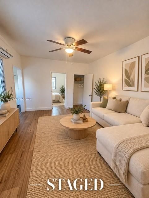 Living area featuring wood-finish flooring, a ceiling fan with integrated lighting, and a reach-in closet