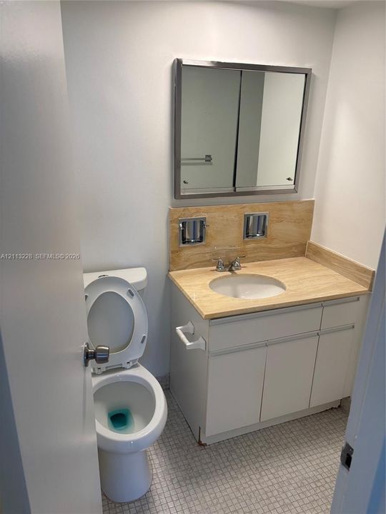 Vanity featuring a stone-finish countertop, integrated basin, neutral cabinetry, and a chrome-framed medicine cabinet