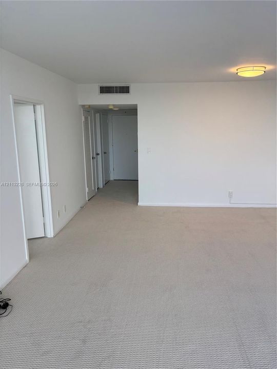 Neutral interior space featuring wall-to-wall carpeting, crisp white wall finishes, and a circular flush-mount ceiling light