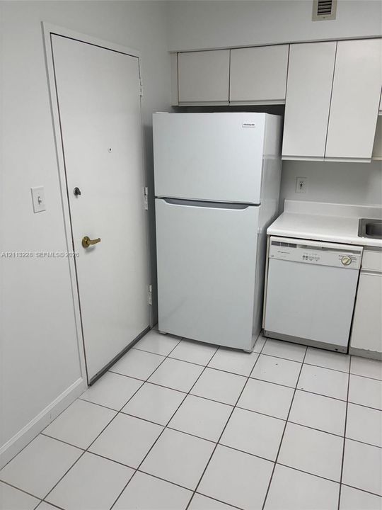 Kitchen area featuring white cabinetry, a built-in refrigerator, a dishwasher, and tile flooring