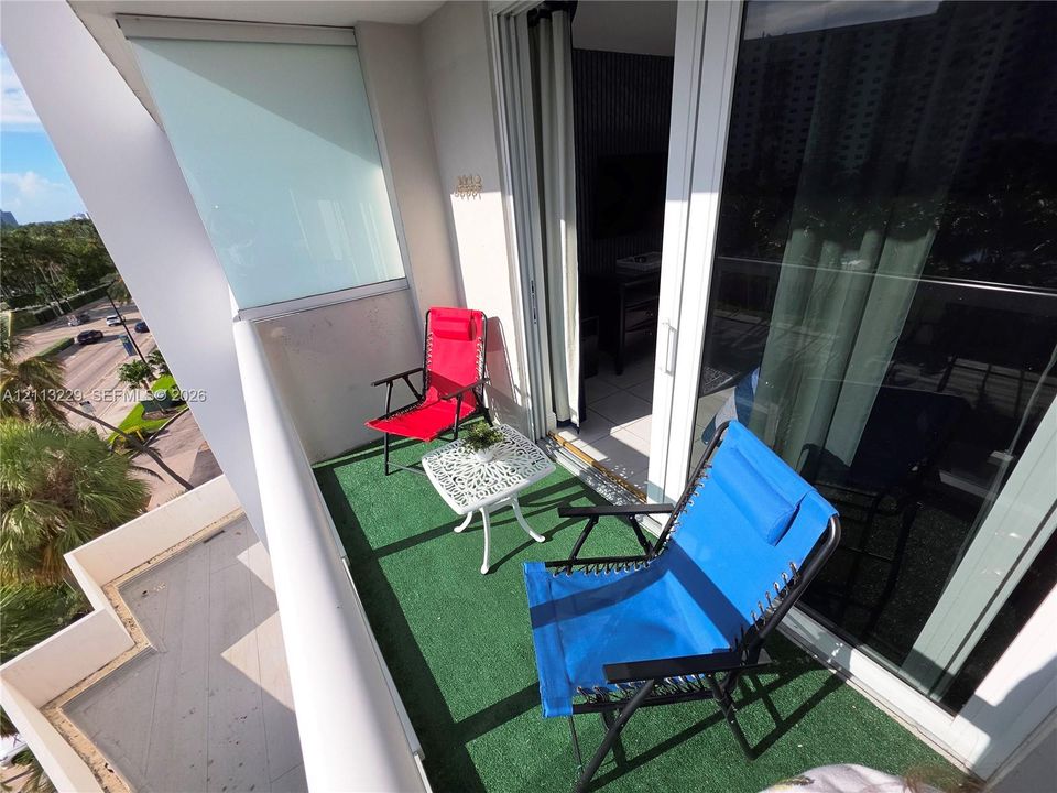 Private covered balcony featuring glass panel railings and sliding glass door access
