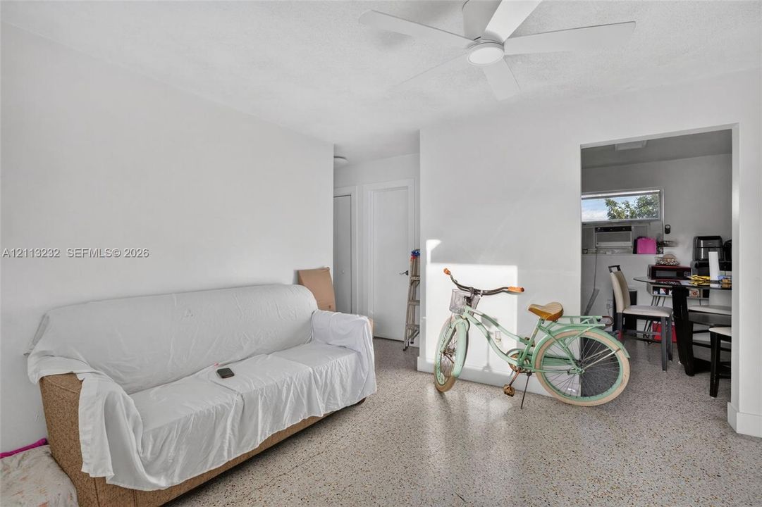Interior space featuring speckled terrazzo flooring, white walls, and a ceiling-mounted fan with integrated lighting