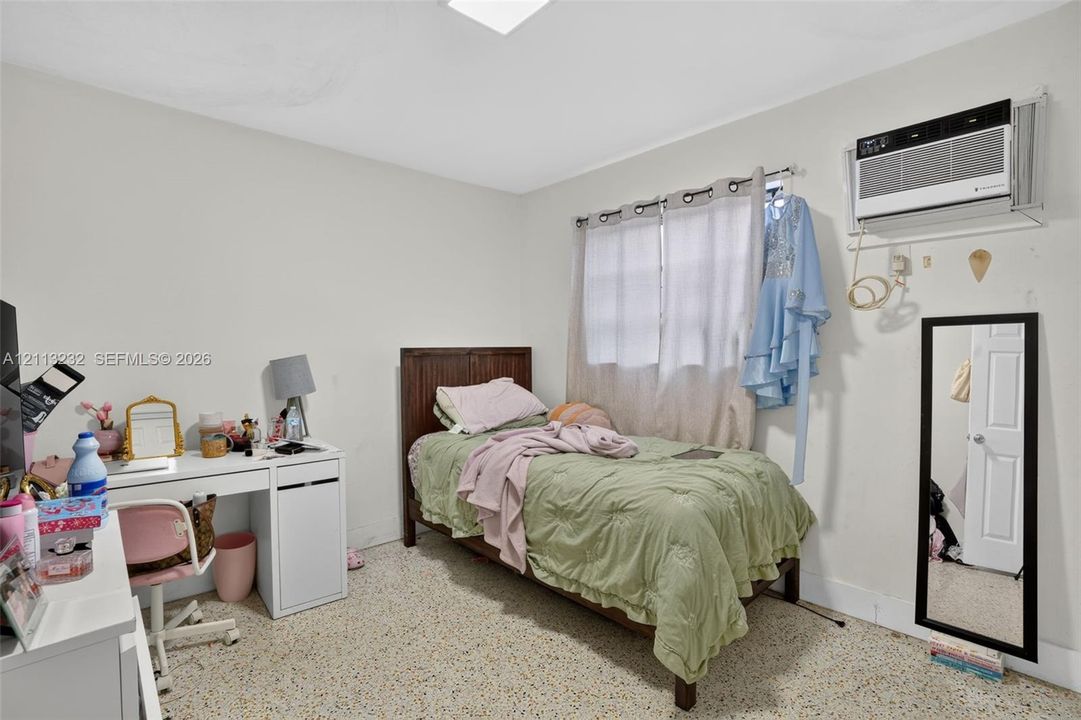 Interior space featuring neutral wall tones, terrazzo flooring, and a wall-mounted climate control unit
