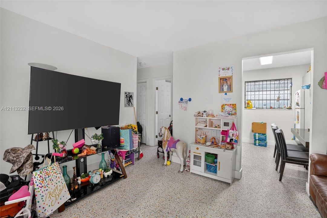 Neutral-toned interior space featuring terrazzo flooring, white interior doors, and a multi-pane window