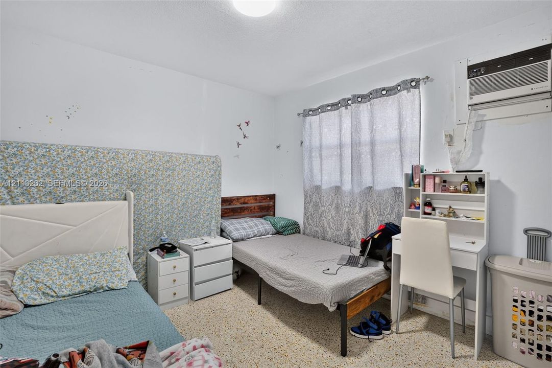Room featuring neutral walls, speckled composition flooring, and a wall-mounted air conditioning unit