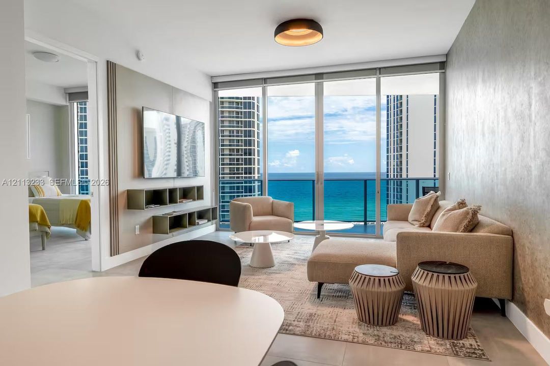 Floor-to-ceiling glass doors, wall-mounted built-in shelving, textured accent wall, and recessed ceiling lighting