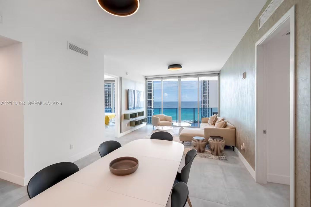 Open-concept interior featuring floor-to-ceiling glass, wall-mounted cabinetry, textured accent wall, and porcelain tile flooring