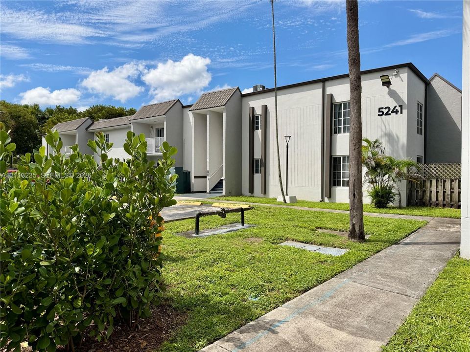 Multi-story exterior featuring a light-toned stucco façade, contrast vertical trim accents, multi-pane windows, and a paved walkway