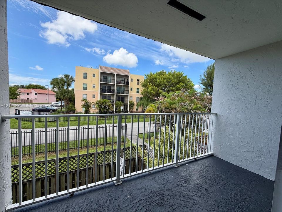 Covered balcony featuring white vertical railing and painted concrete flooring