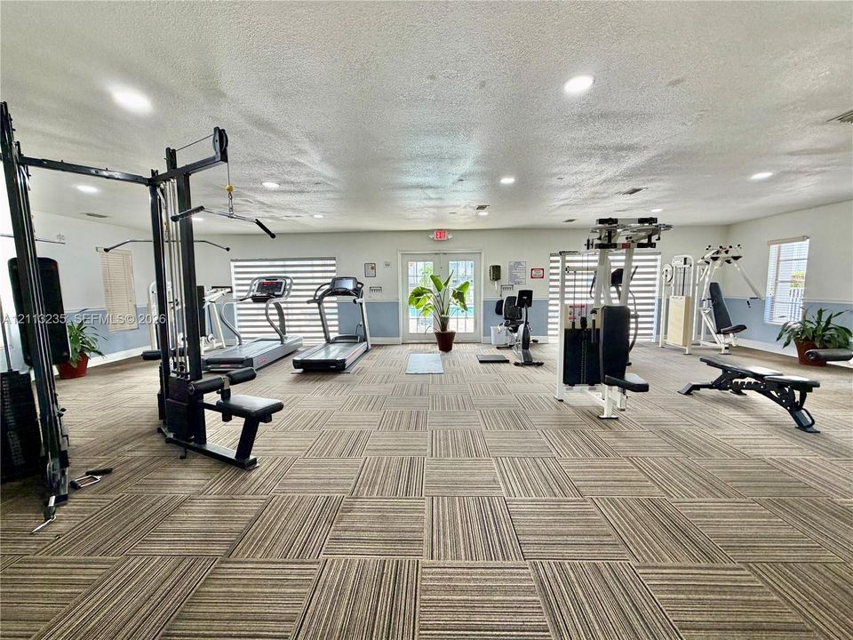 Fitness room featuring modular carpet tile flooring, recessed lighting, and double glass-paned doors