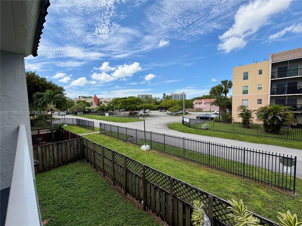 Enclosed green space featuring a wood-style privacy fence, metal perimeter fencing, and mature landscaping