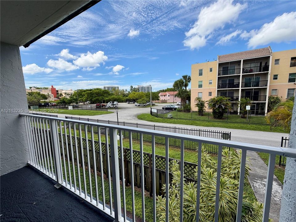 Covered balcony featuring white vertical railing and textured flooring