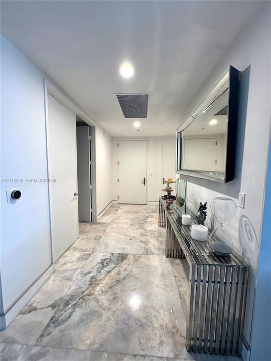 Foyer featuring large-format stone flooring, recessed lighting, and a solid-core door