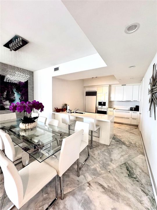 Kitchen featuring white cabinetry, solid-surface countertops, built-in appliances, and light-toned stone-finish flooring with geometric tile patterns