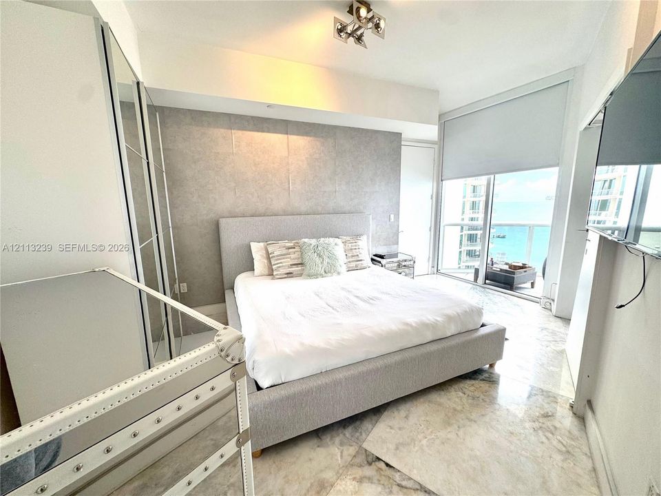 Floor-to-ceiling sliding glass doors, marble flooring, textured accent wall, and built-in mirrored wardrobe