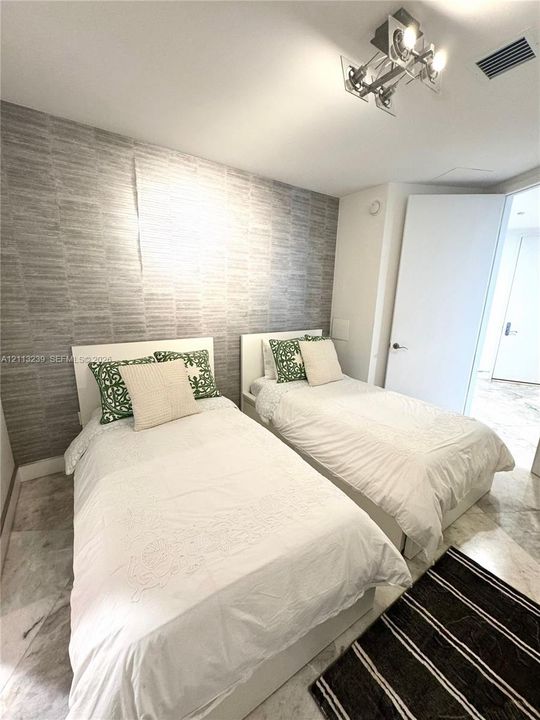 Bedroom featuring stone flooring, textured wall covering, and a multi-directional track lighting fixture