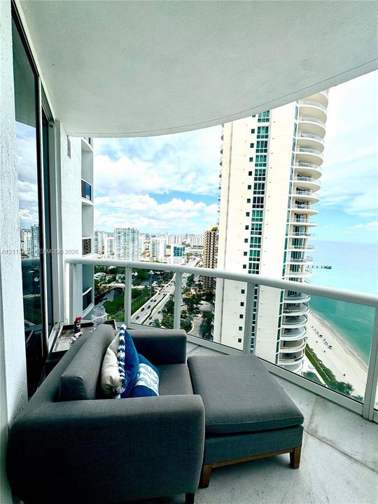 Curved private balcony featuring a glass panel railing and tile flooring