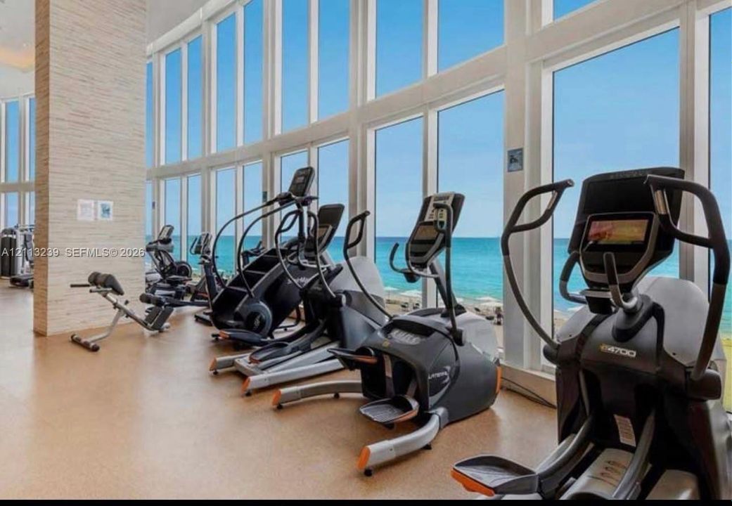 Fitness center featuring floor-to-ceiling windows, a stacked stone column, and neutral flooring