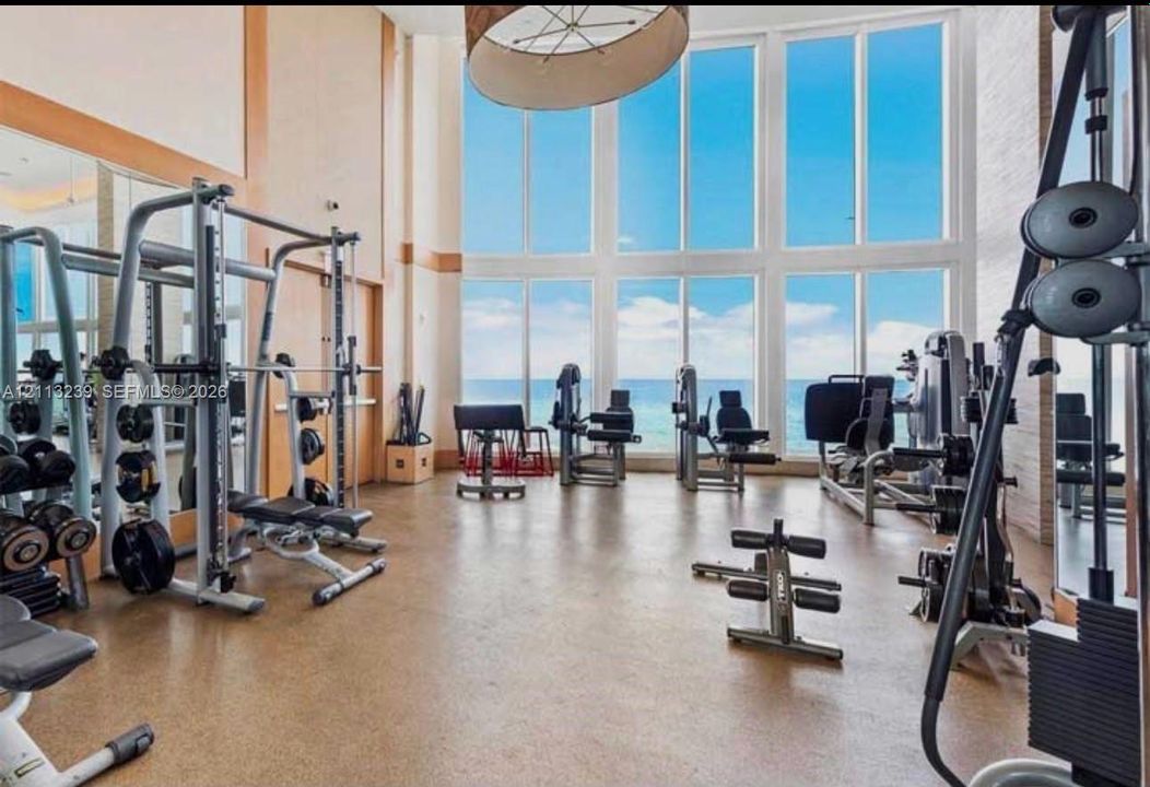 Fitness area featuring floor-to-ceiling windows, high ceilings, large-format tile flooring, and wall-to-wall mirrors