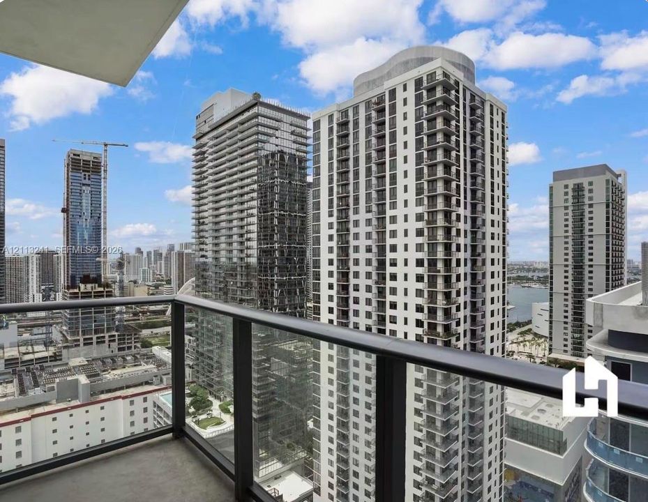 Private balcony with a glass and metal railing, showcasing an expansive urban skyline