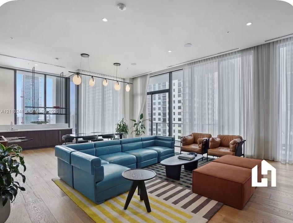 Open-concept interior featuring wood-finish flooring, floor-to-ceiling windows, recessed lighting, and a built-in wet bar with dark cabinetry