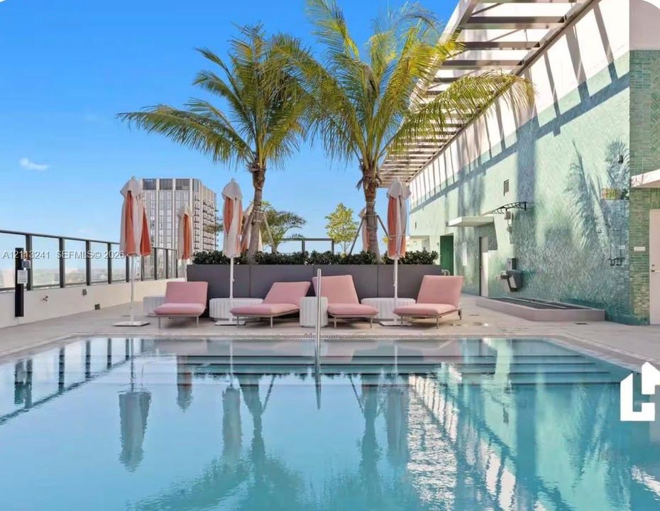 Rooftop swimming pool featuring a tiled accent wall, glass panel railing, built-in planters, and a shaded pergola structure